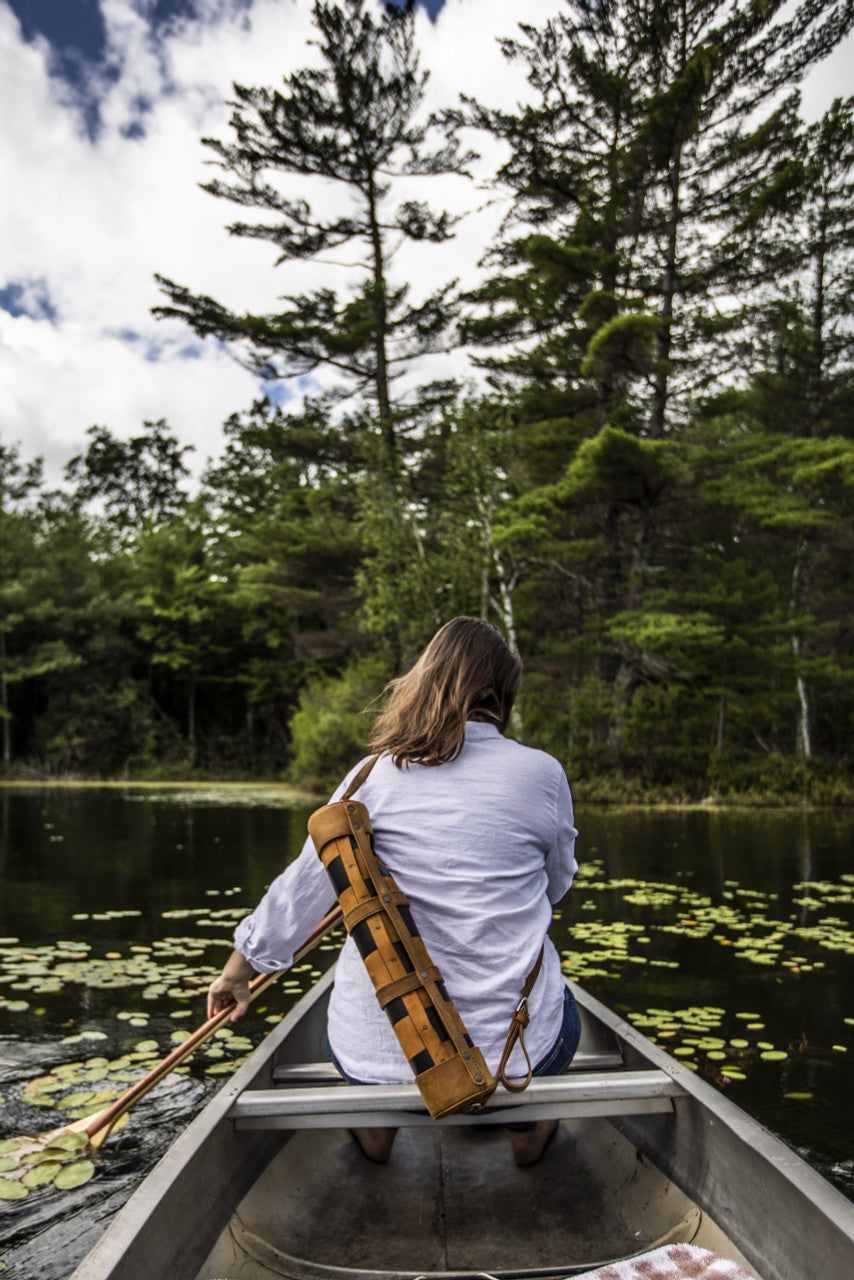 Leather Travel Chess Set in Tobacco carried across the back of a woman paddling a canoe on a lake