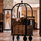 Leather Trunk in Tobacco stacked with leather bags on a brass luggage cart in a hotel lobby