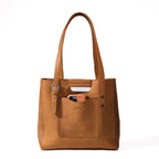 Everyday Leather Tote in Tobacco, front view with embossed logo, front slip pocket and buckled side strap
