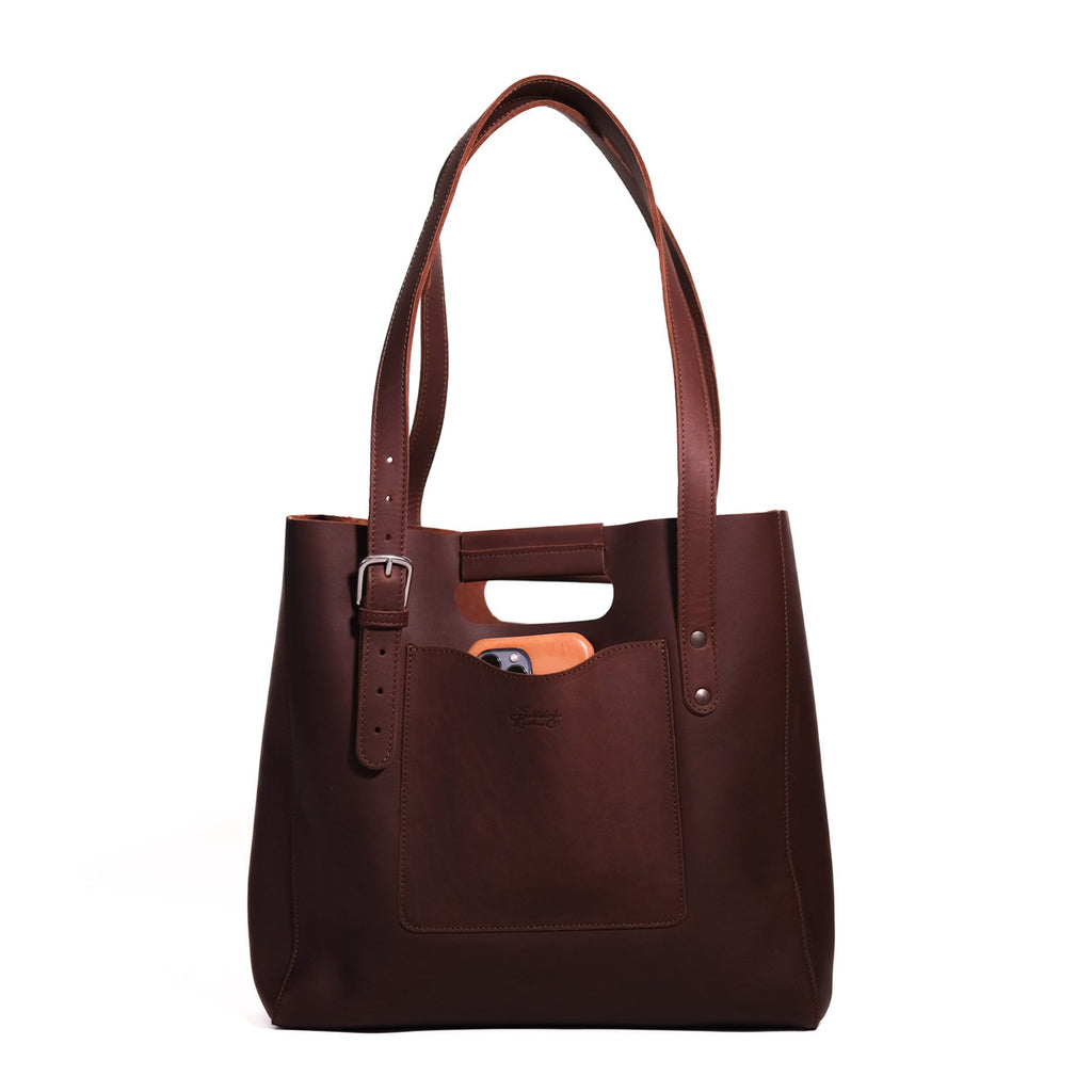 Everyday Leather Tote in Chestnut, front view with shoulder handles, buckled side strap and a phone in the front pocket