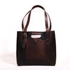 Everyday Leather Tote in Dark Coffee Brown, front view with shoulder handles, buckled side strap and a phone in the front pocket