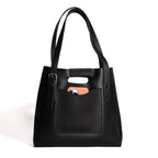Everyday Leather Tote in Black, front view with shoulder handles, buckled side strap and a phone in the front pocket