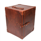 Leather Small Trunk in Chestnut, standing upright and closed with top handle, buckled strap and leather corner guards