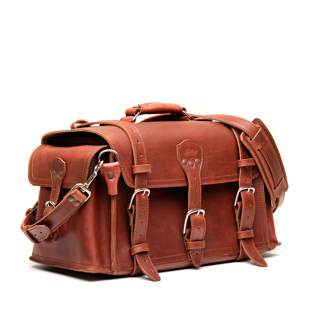 Side Pocket Leather Duffle in Chestnut, angled front view with buckle straps, side pocket and shoulder strap
