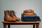 Italian Dress Belt in English Tan, coiled on folded jeans beside tan leather boots