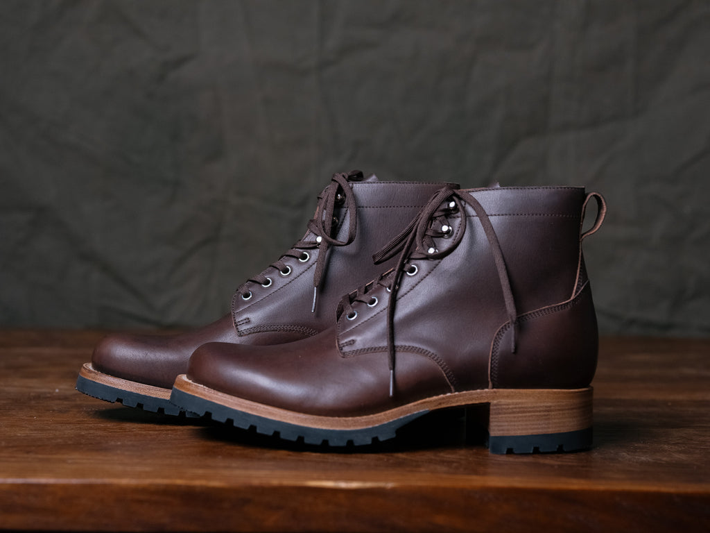 Huntsman Boots in Dark Coffee Brown, pair with lug soles and stacked heels on a wooden table