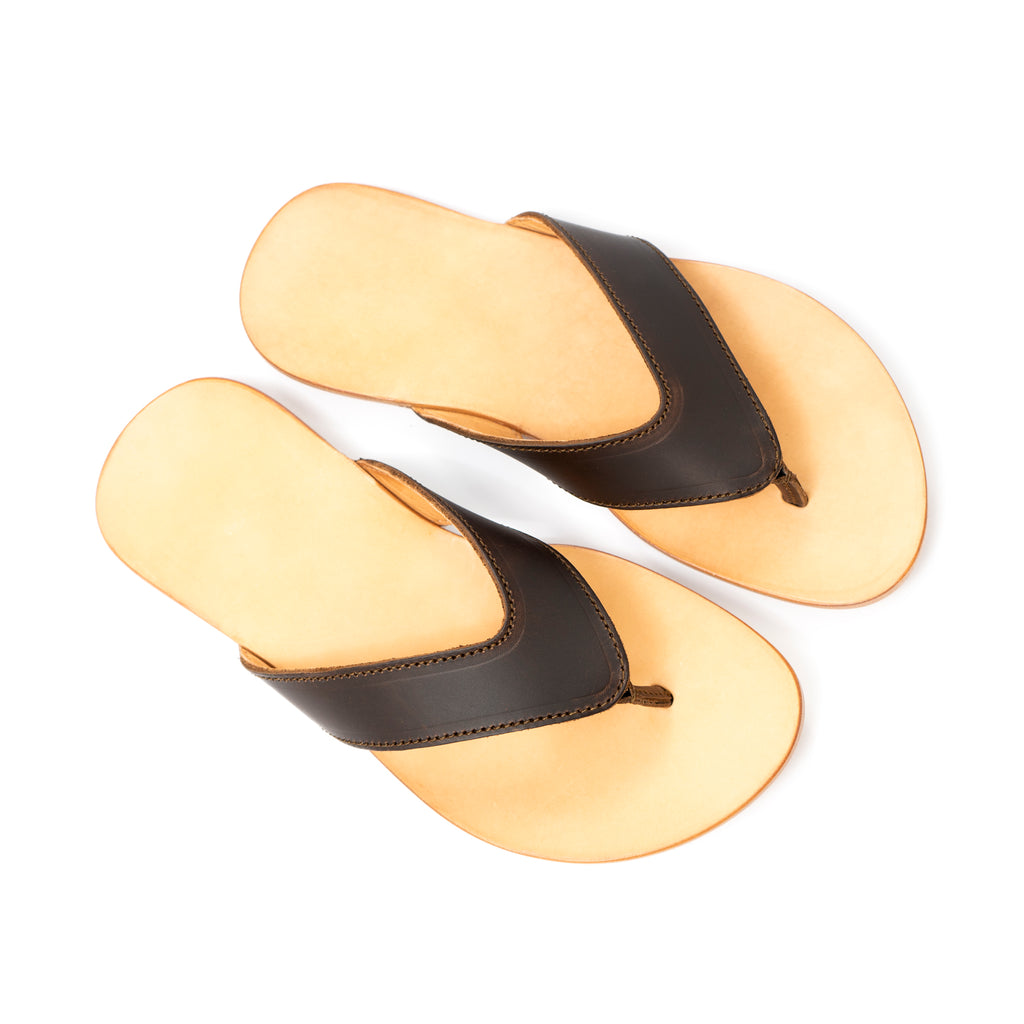Pair of Flip Flops in Dark Coffee Brown leather with V-shaped thong straps and natural footbeds, angled view