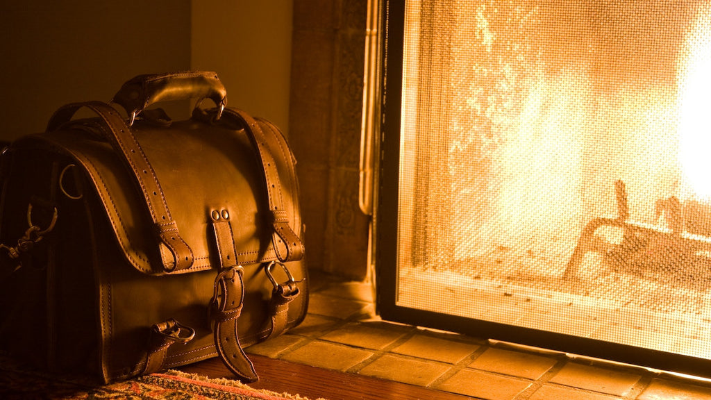 Large Classic Leather Briefcase beside a glowing fireplace on a tiled hearth in warm firelight