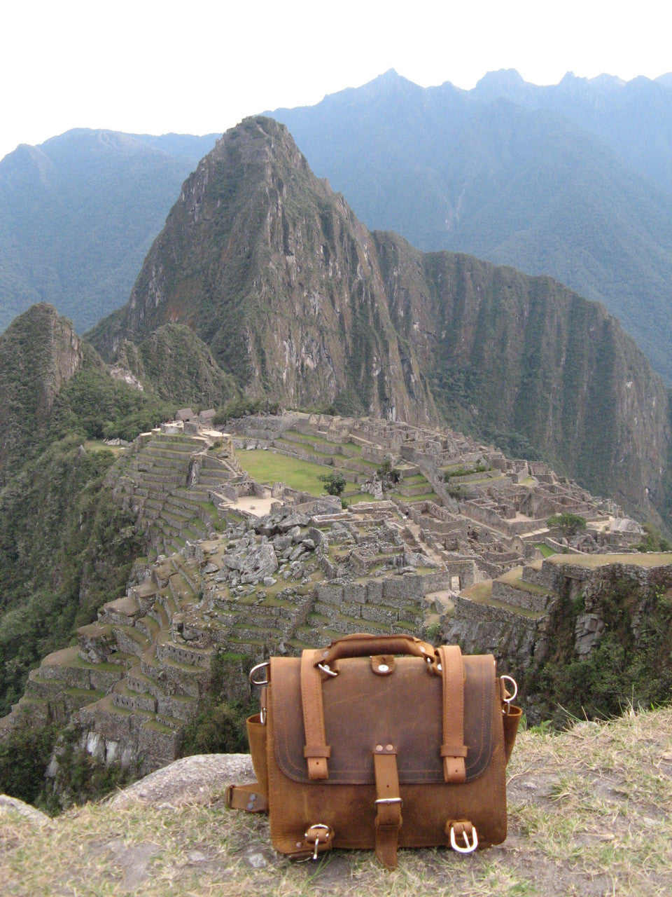 Large Classic Leather Briefcase in Tobacco on a grassy ledge overlooking the ruins of Machu Picchu