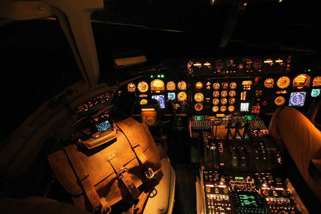 Large Classic Leather Briefcase on a pilot seat in a dark airliner cockpit lit by glowing instrument panels