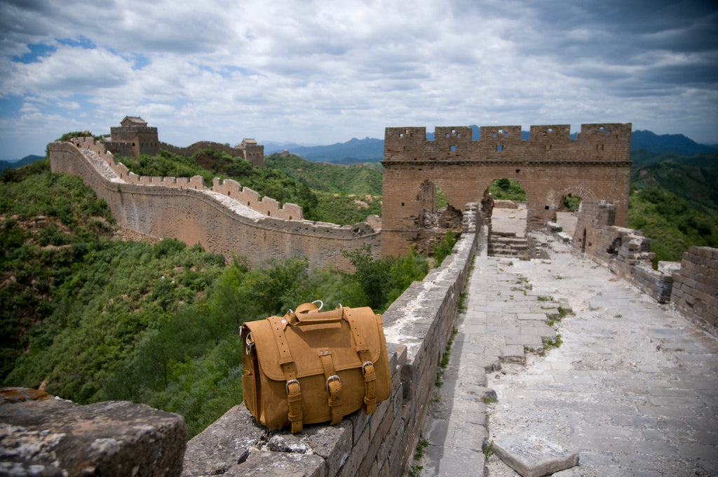 Large Classic Leather Briefcase in Tobacco resting on the Great Wall of China with green hills and a watchtower