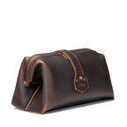 Big Mouth Leather Toiletry Bag in Dark Coffee Brown, angled back view showing riveted strap end