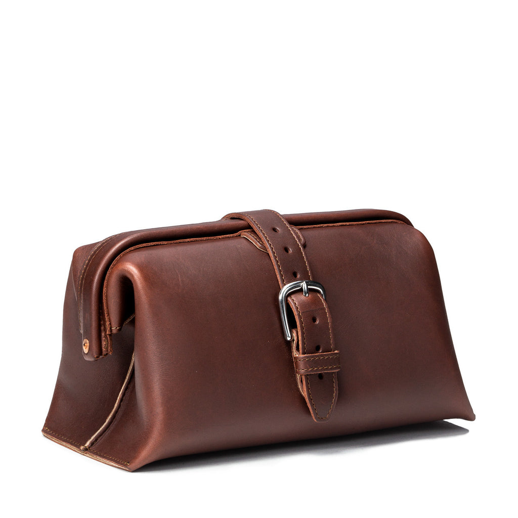 Big Mouth Leather Toiletry Bag in Chestnut, angled front view with buckle strap closure