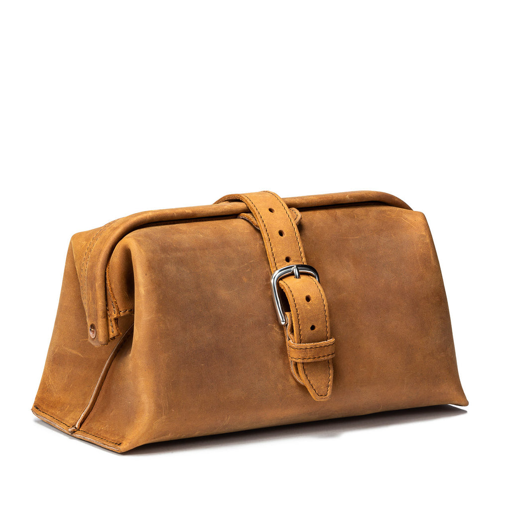 Big Mouth Leather Toiletry Bag in Tobacco, angled front view with buckle strap closure