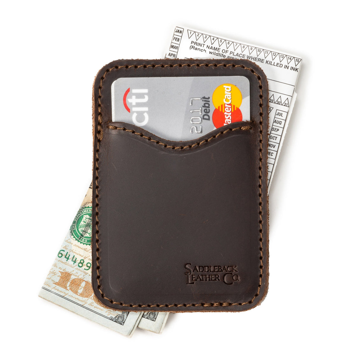 Slim Leather Card Wallet in Dark Coffee Brown lying flat with a debit card in the front pocket over cash and a receipt
