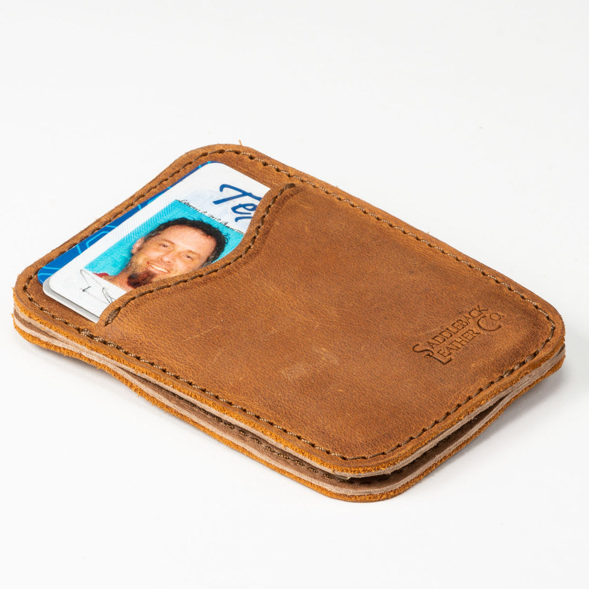 Slim Leather Card Wallet in Tobacco lying flat at an angle with an ID card in the front pocket