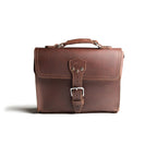 Front Pocket Leather Satchel in Chestnut, straight-on front view with riveted buckle strap and top handle