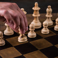 Leather Travel Chess Set, close-up of a hand moving a wooden pawn on the leather checkerboard