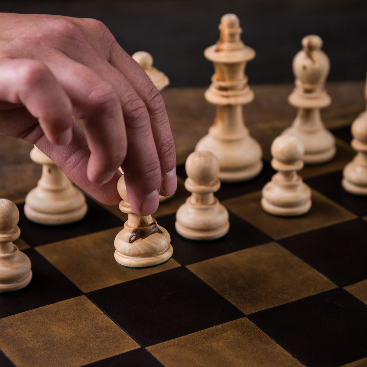 Leather Travel Chess Set, close-up of a hand moving a wooden pawn on the leather checkerboard