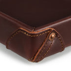The Leather Grandfather Valet Tray in Chestnut, close-up of a stitched corner tab with copper rivet