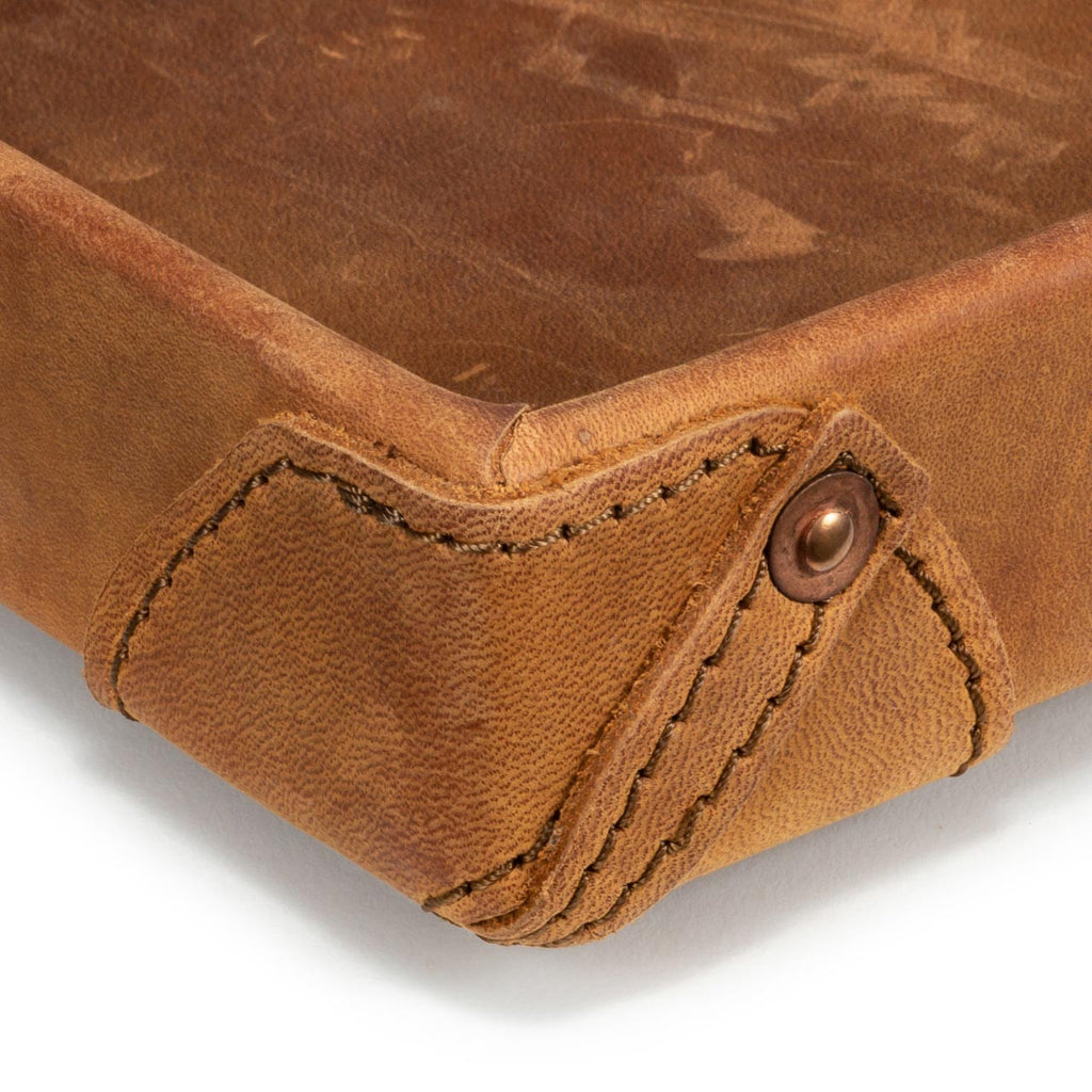 The Leather Grandfather Valet Tray in Tobacco, close-up of a stitched corner tab with copper rivet