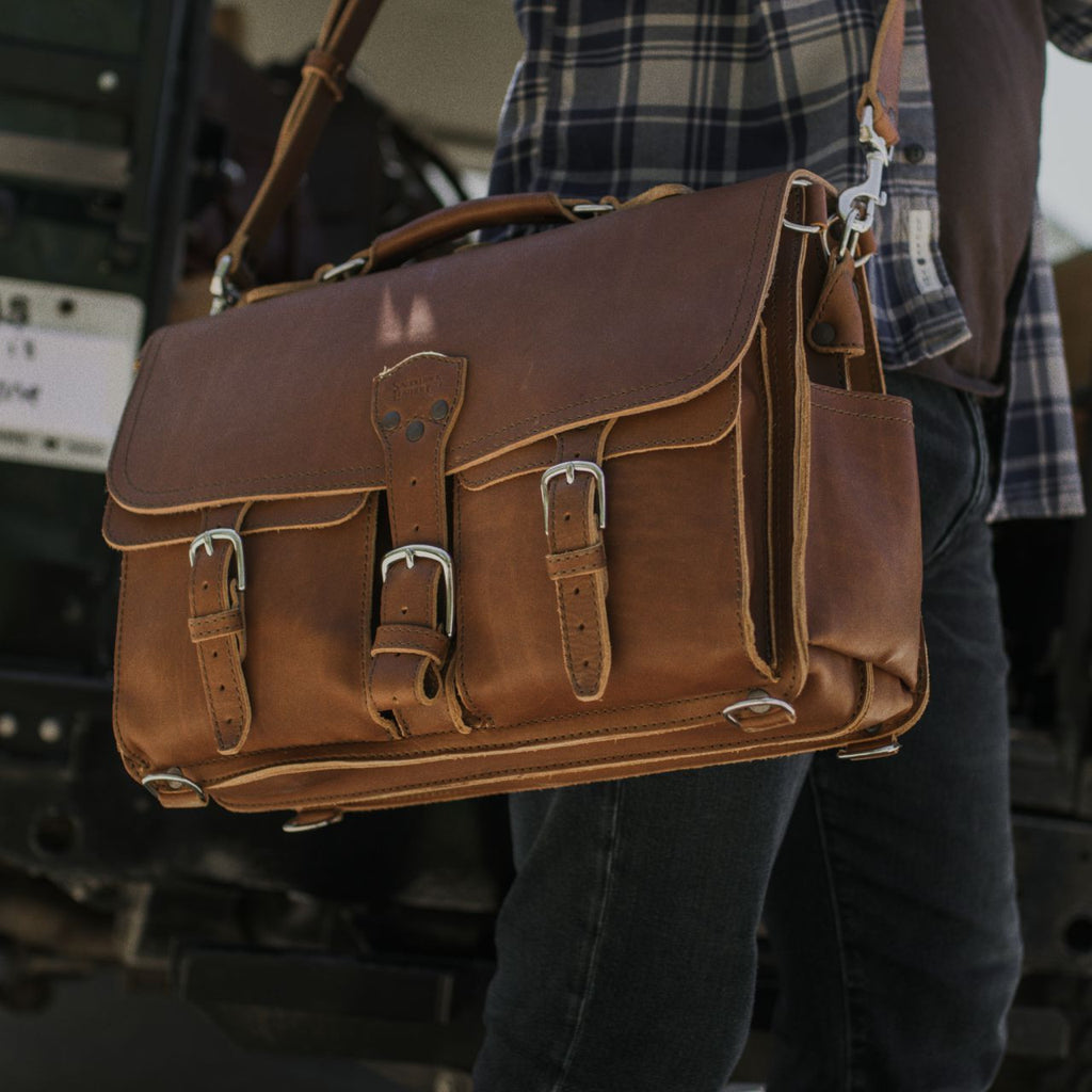 Front Pocket Leather Briefcase in Tobacco carried on the shoulder by a person in a flannel shirt and jeans
