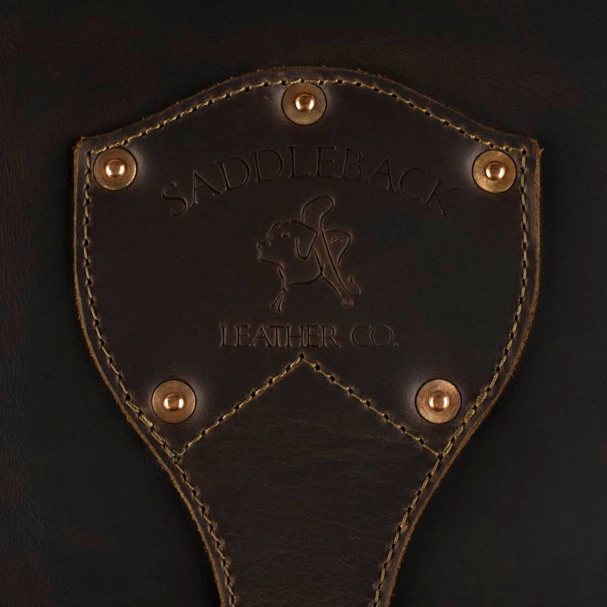 Leather Trunk in Dark Coffee Brown, close-up of riveted shield patch embossed with Saddleback Leather Co. logo