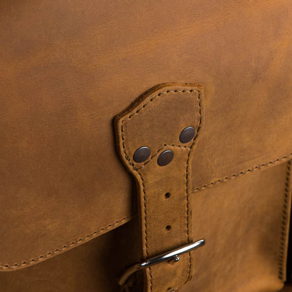 Leather Trunk in Tobacco, close-up of a buckled lid pocket with riveted strap