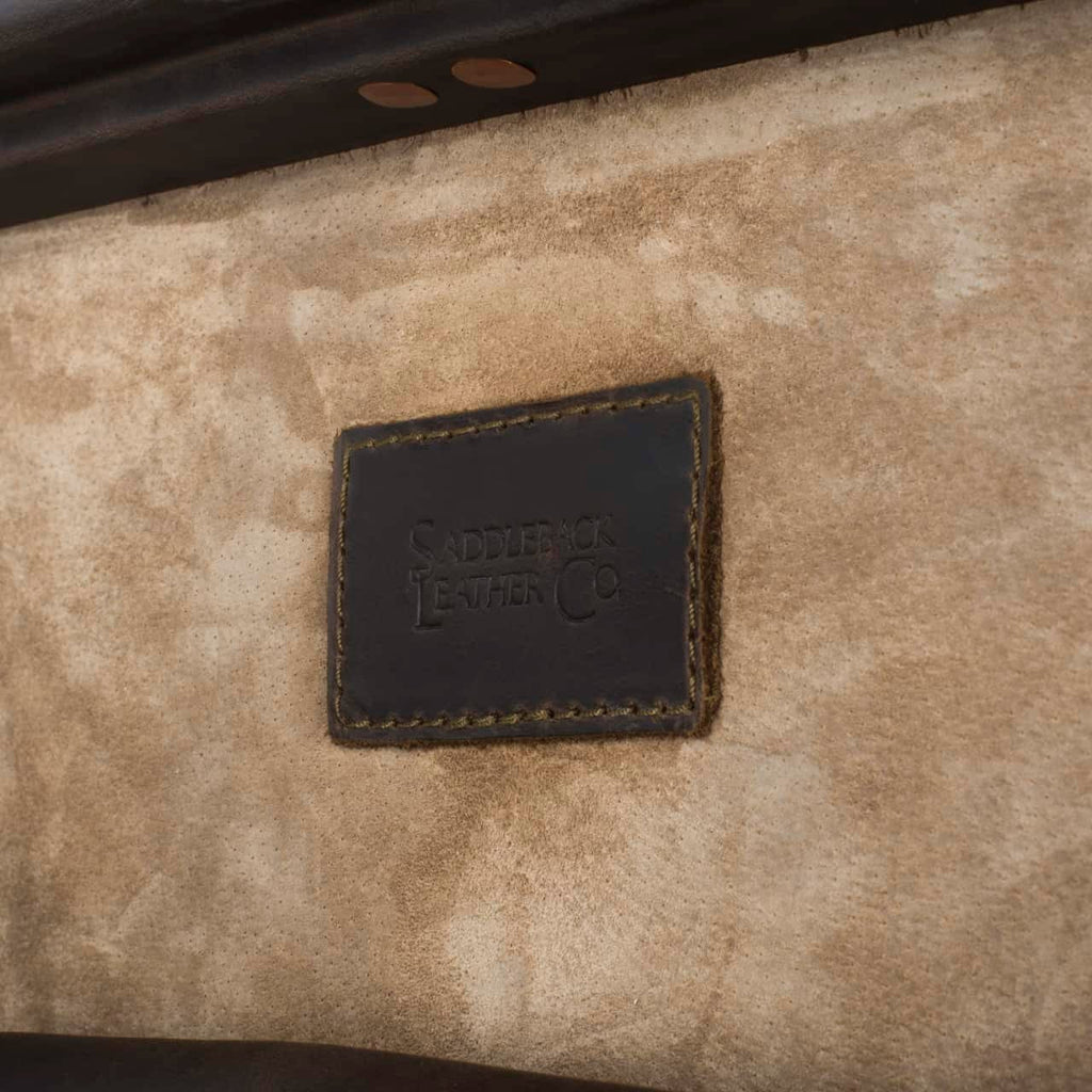 Leather Trunk in Dark Coffee Brown, close-up of stitched logo patch on the suede interior of the lid
