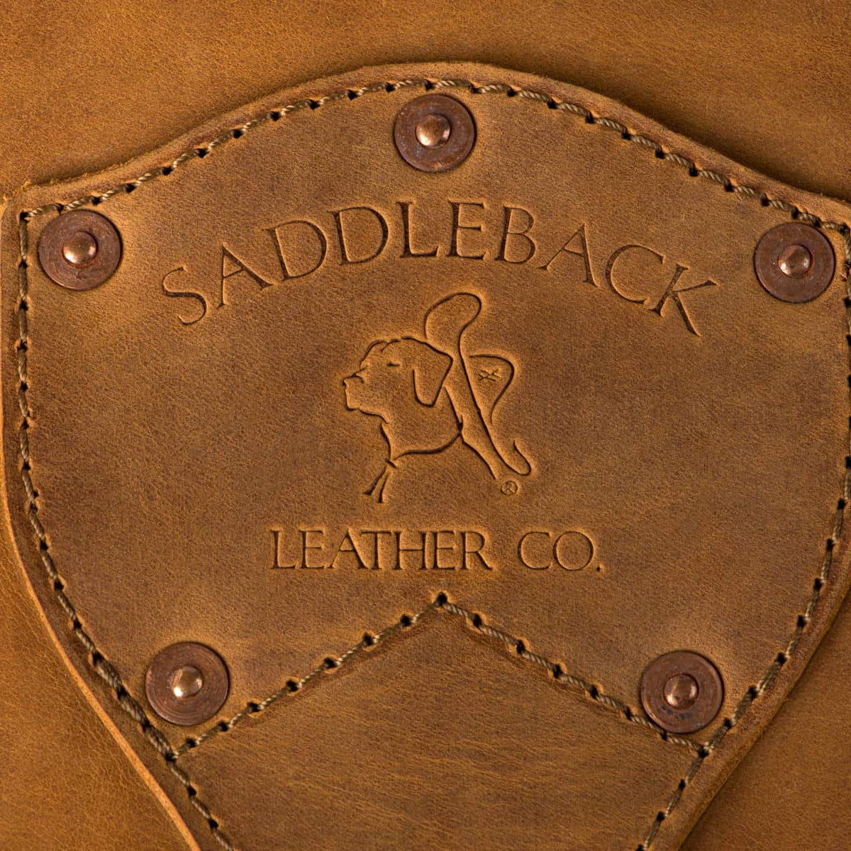 Leather Trunk in Tobacco, close-up of riveted shield patch embossed with Saddleback Leather Co. and dog logo