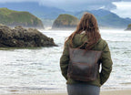 Universal Leather Backpack in Dark Coffee Brown worn by a woman standing at the ocean shore