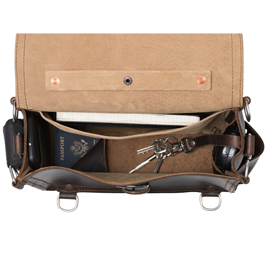 Photographer's Satchel in Dark Coffee Brown, top view open with a passport, keys and notebook inside