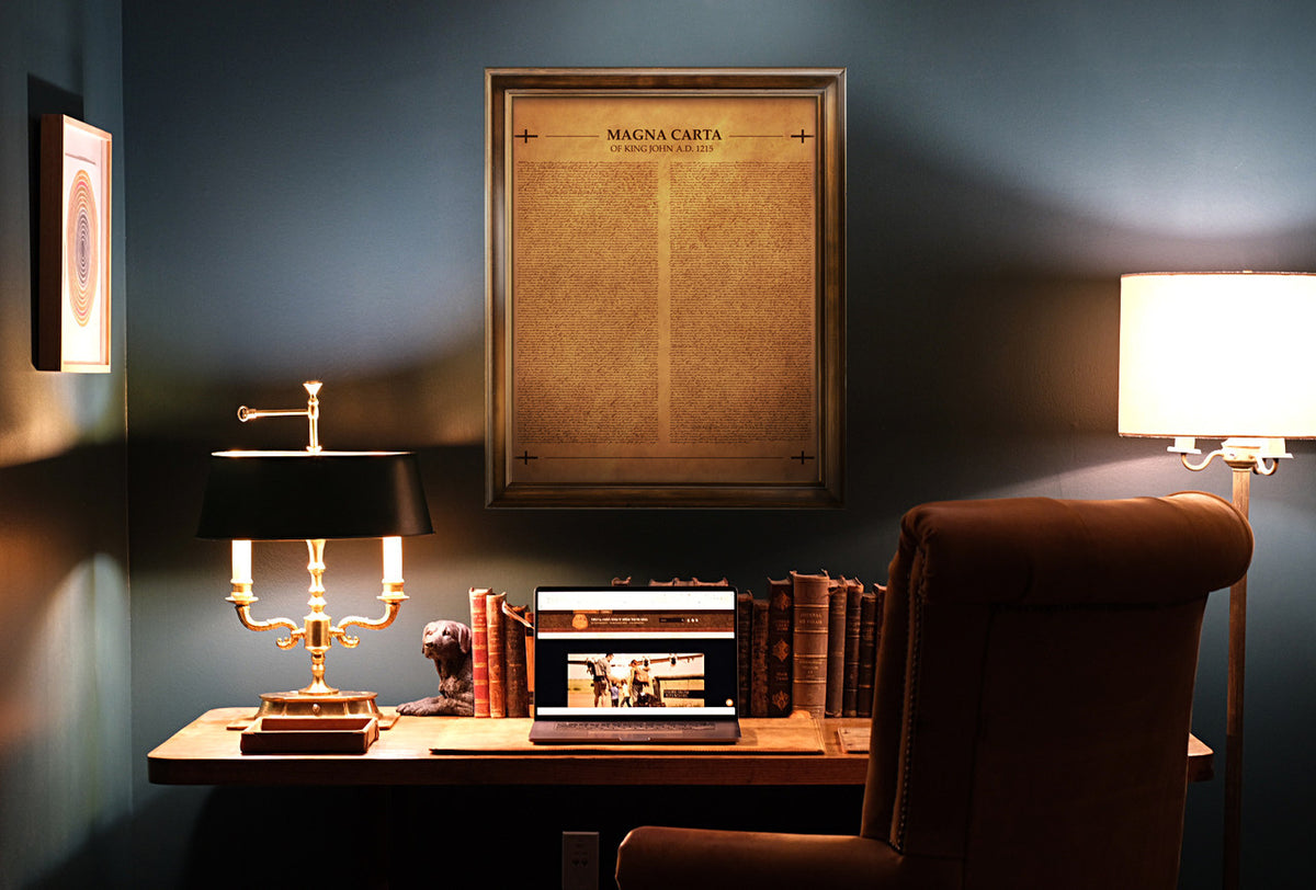 Leather Magna Carta in tan, framed on the wall above a desk with lamps and books in a dim study