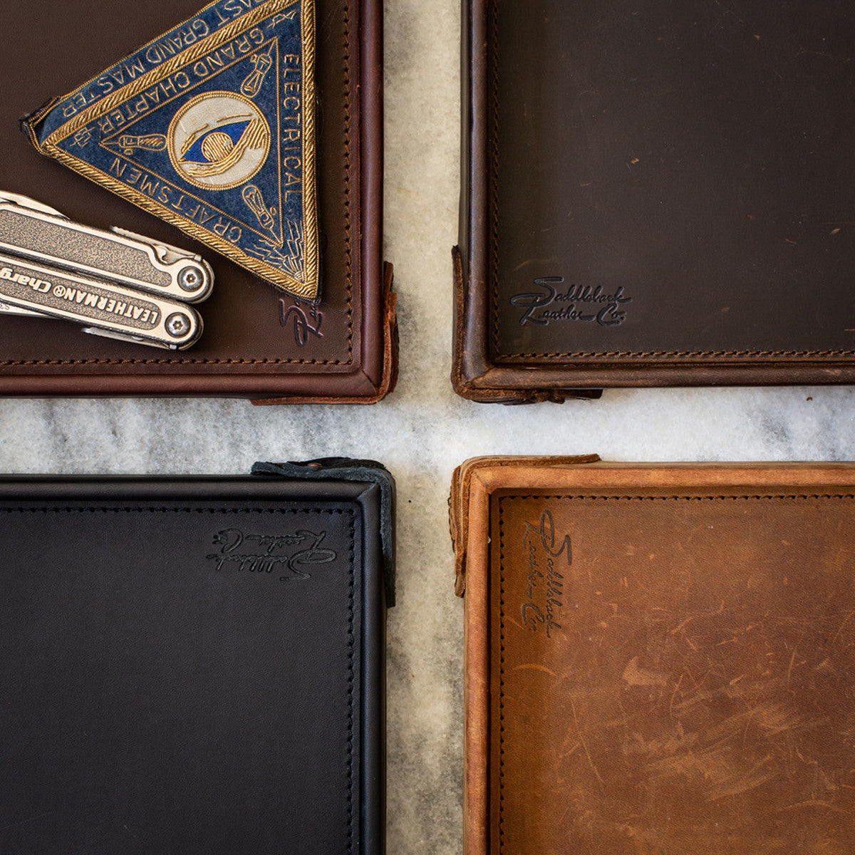 The Leather Grandfather Valet Tray in Chestnut, Dark Coffee Brown, Black and Tobacco, corners meeting on marble