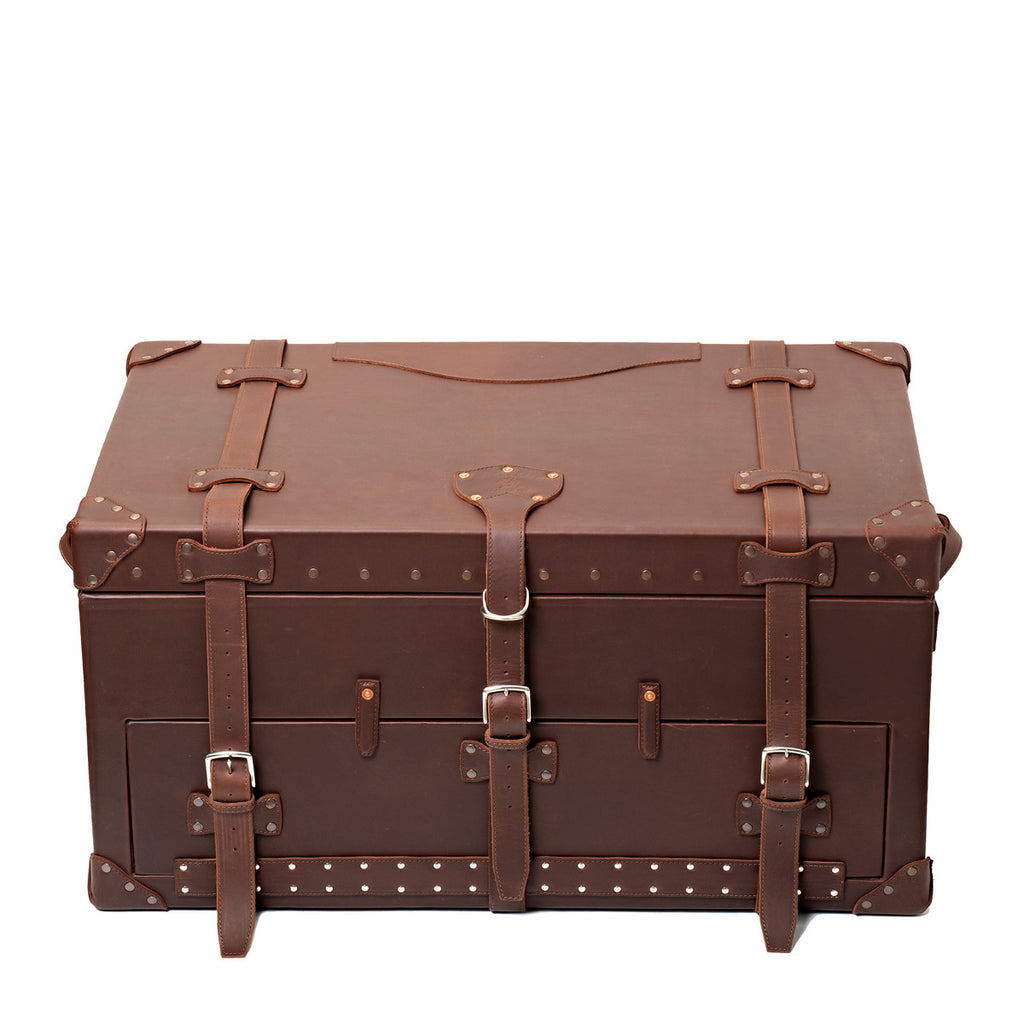Leather Trunk in Chestnut, closed front view with three buckled straps, studded trim and corner guards