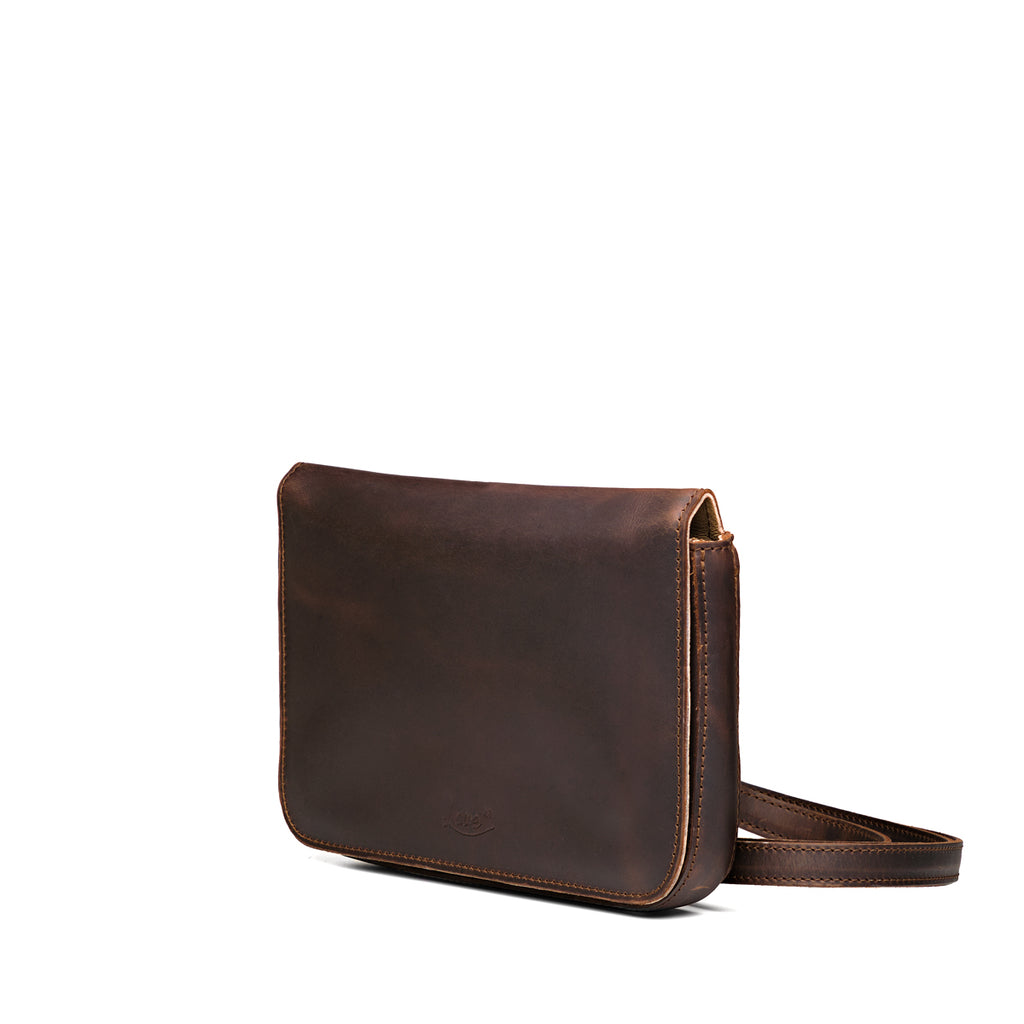 Magnetic Fold Over Bag Medium in Dark Coffee Brown, angled side view with strap resting beside the bag