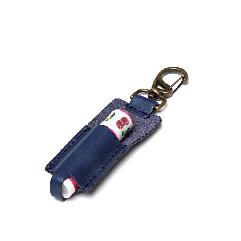 Leather Chapstick Holder in navy blue, holding a lip balm with brass swivel clasp keychain