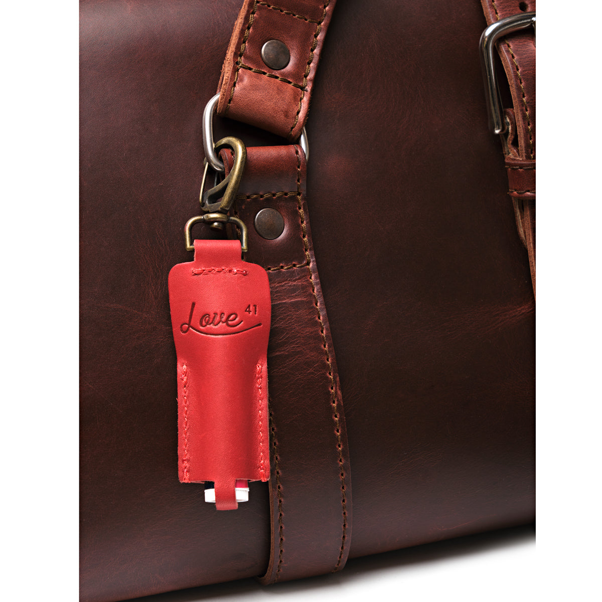 Leather Chapstick Holder in red, clipped to the strap ring of a dark brown leather bag