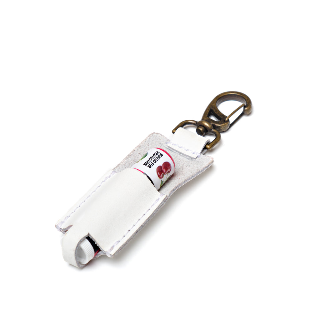 Leather Chapstick Holder in white, holding a lip balm with brass swivel clasp keychain