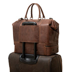 Two Compartment Duffle in Dark Coffee Brown, back trolley sleeve slid over a rolling suitcase handle