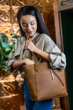 Concealed Carry Leather Tote in Tobacco, woman reaching into the tote while carrying it on her shoulder