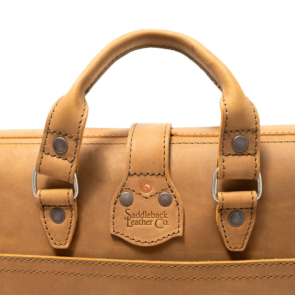 Flight Bag Leather Briefcase in tan, close-up of the top handle and riveted tab with embossed Saddleback Leather Co. logo