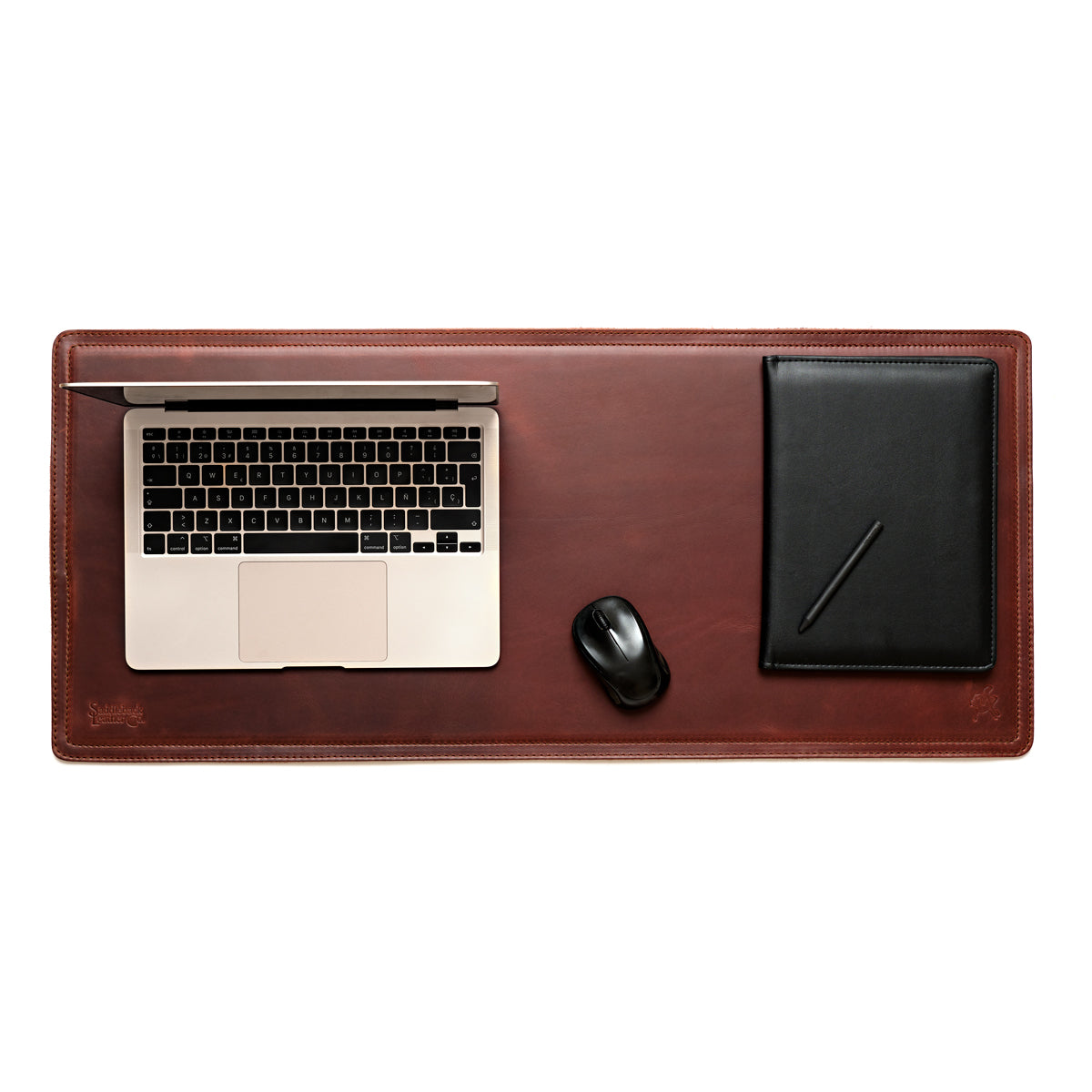 Long Desk Pad in Chestnut styled as a workspace with a laptop, mouse and black notebook, overhead view