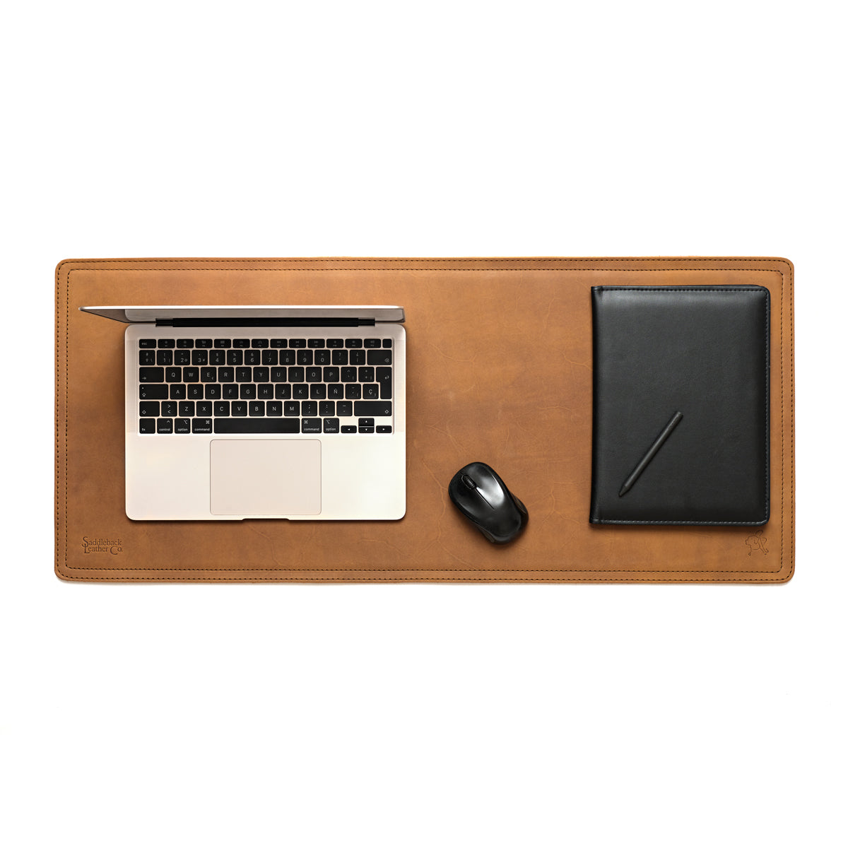 Long Desk Pad in Tobacco leather styled as a workspace with a laptop, mouse and black notebook, overhead view