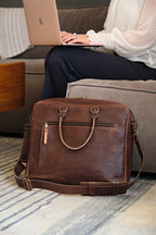 Women's Business Satchel in Chestnut, standing on a striped rug beside a woman working on a laptop