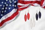 Leather Feather Earrings in Red, White and Dark Blue laid on white fabric beside a draped American flag