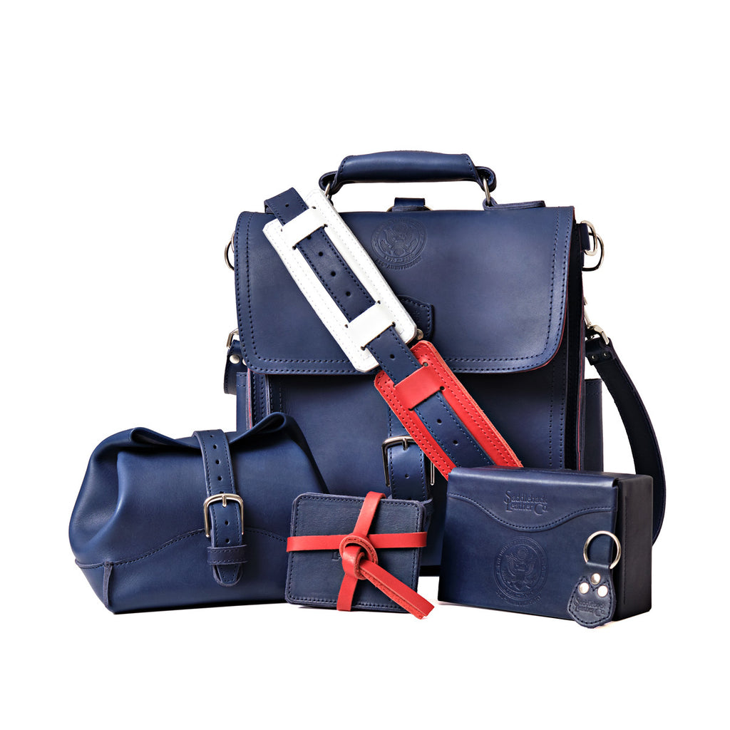 Saddleback Club Membership 250th Anniversary collection in Blue and Red with messenger bag, toiletry bag, coasters and desk box
