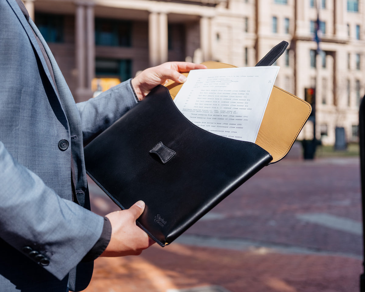 Silverback Document Holder in Black, flap open as papers are pulled out on a city street
