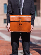 Silverback Document Holder in English Tan, held in front of a man in a dark suit outdoors