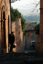 Wesley Deep Pocket Duffle in Raven Black, carried down a narrow brick alley in a hillside village